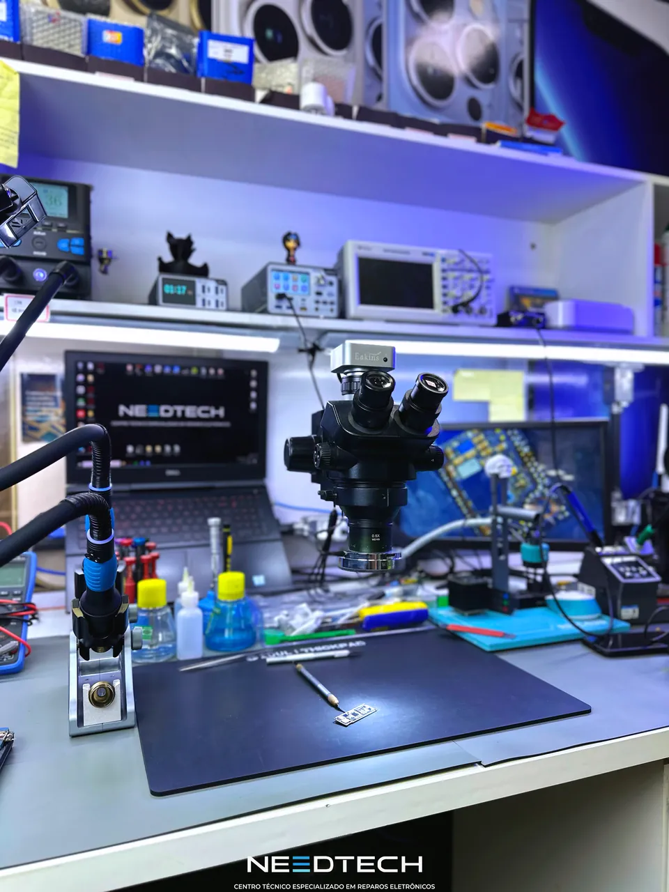 Bancada técnica da NeedTech com microscópio e instrumentos de reparo